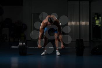 Muscular Hispanic Man Doing Heavy Weight Exercise For Back With Barbell In Modern Gym