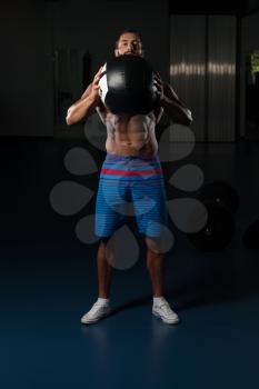 Latin Male Athlete Crouched Doing Wall Balls Exercises At The Gym