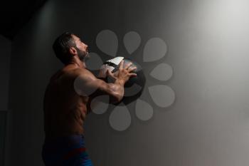 Latin Male Athlete Crouched Doing Wall Balls Exercises At The Gym