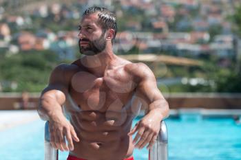 Portrait Of A Wet Sexy Muscular Man Standing In Swimming Pool