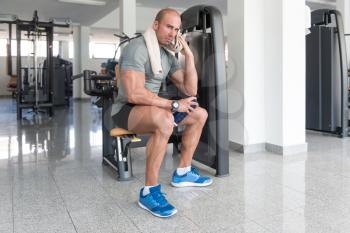 Muscular Man Resting After Exercise And Wipes The Sweat With Towel