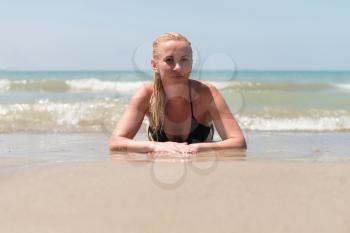 Young Beautiful Wet Blonde Woman Lying on the Beach Sand Near Ocean