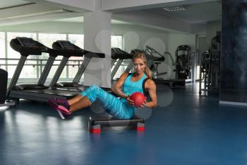 Mature Woman Athlete Doing Abs Exercise With Ball On Stepper As Part Of Bodybuilding Training