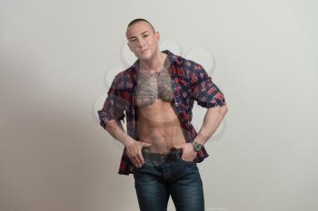 Portrait of a Strong Man In Shirt Showing His Abs Standing Isolated on Gray Background