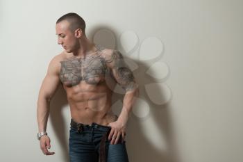 Portrait of a Strong Man In Pants Showing His Abs Standing Isolated on Gray Background