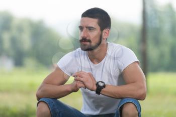 Portrait Of A Young Man Sitting on Grass - Handsome Guy Repose in Nature - Outdoors - Outside