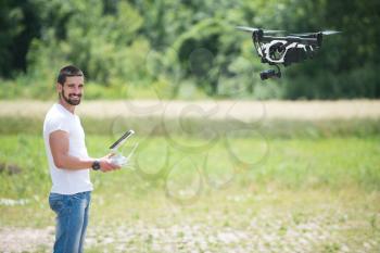 Man Operating Drone Flying or Hovering by Remote Control in Nature