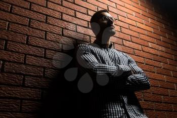 Portrait Of A Young Physically Fit Man in Shirt Posing On Wall of Bricks