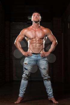 Handsome Young Man In Jeans Standing Strong In The Gym And Flexing Muscles - Muscular Athletic Bodybuilder Fitness Model Posing After Exercises