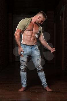 Handsome Young Man In Jeans & T-shirt Standing Strong In The Gym And Flexing Muscles - Muscular Athletic Bodybuilder Fitness Model Posing After Exercises
