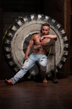 Athletic Man In Jeans Pants Resting - Workout At Gym With Hammer And Tractor Tire