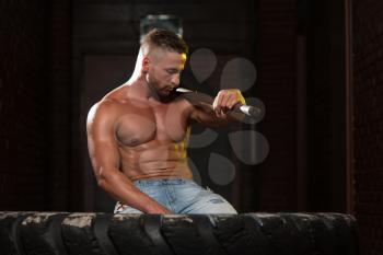 Athletic Man In Jeans Pants Resting - Workout At Gym With Hammer And Tractor Tire