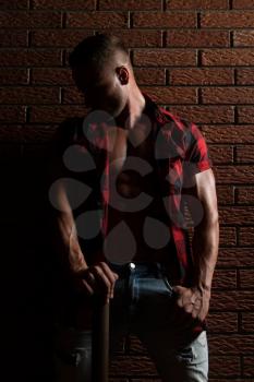 Portrait Of A Young Physically Fit Man Showing His Well Trained Body While Wearing Plaid Shirt - Muscular Athletic Bodybuilder Fitness Model Posing After Exercises On Wall of Bricks
