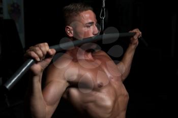 Muscular Athletic Bodybuilder Fitness Model Doing Heavy Weight Exercise For Back On Machine