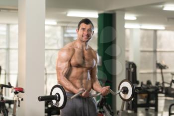 Healthy Hairy Man Working Out Biceps In A Fitness Center Gym