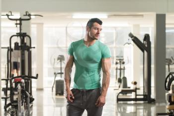Healthy Young Man in T-shirt Standing Strong and Flexing Muscles - Muscular Athletic Bodybuilder Fitness Model Posing After Exercises