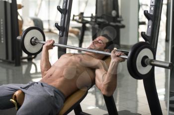 Muscular Hairy Man Doing Heavy Weight Exercise For Chest With Barbell In Gym