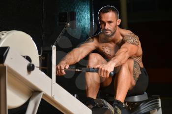 Young Strong Man In The Gym And Exercising Back On Machine - Muscular Athletic Bodybuilder Fitness Model Exercise