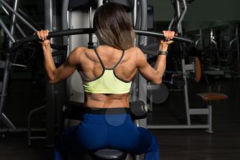 Fitness Woman Working Out Back On Machine In Fitness Center