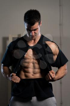 Handsome Man Standing Strong In The Gym And Ripping the T-Shirt Off - Muscular Athletic Bodybuilder Fitness Model Posing After Exercises