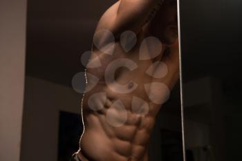 Portrait Of A Young Physically Fit Man Showing His Well Trained Abdominal Muscle - Muscular Athletic Bodybuilder Fitness Model Posing After Exercises