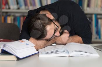Sleeping Caucasian Student Sitting And Leaning On Pile Of Books In College - Shallow Depth Of Field