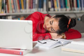 Sleeping Woman Student Sitting And Leaning On Pile Of Books In College - Shallow Depth Of Field