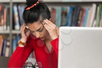 Stressed Student Of High School Sitting At The Library Desk - Shallow Depth Of Field