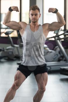 Healthy Man In Undershirt Standing Strong At Gym And Flexing Muscles - Muscular Athletic Bodybuilder Fitness Model Posing After Exercises