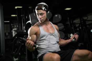 Young Bodybuilder Doing Heavy Weight Exercise For Biceps On Machine