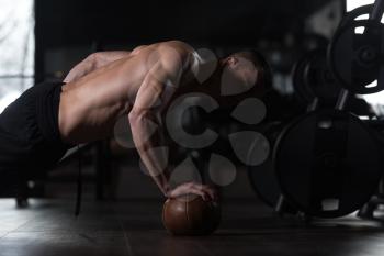 Young Man Athlete Doing Pushups On Ball With One Hand As Part Of Bodybuilding Training