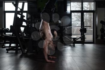 Young Man Athlete Doing Extreme Handstand On One Hand As Part Of Bodybuilding Training