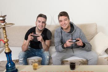 Two Brothers or Friends Playing Video Games Together as They Relax on a Couch in the Living Room