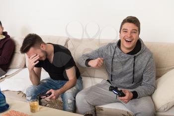 Three Young Brothers Having Happy Time Together Playing Video Games At Home