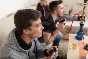 Three Young Brothers Having Happy Time Together Playing Video Games At Home