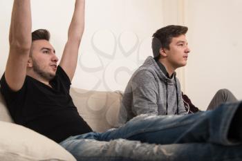 Two Young Brothers Having Happy Time Together Playing Video Games At Home
