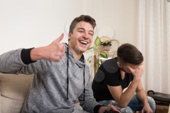 Two Young Brothers Having Happy Time Together Playing Video Games At Home