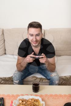 Young Man Having Happy Time Playing Video Games At Home