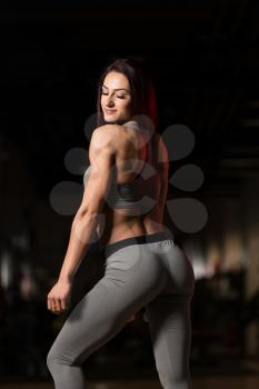 Attractive Young Woman Standing Strong In The Gym And Flexing Muscles - Beautiful Athletic Fitness Model Posing After Exercises