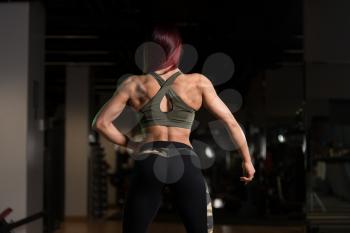 Healthy Young Woman Standing Strong In The Gym And Flexing Muscles - Beautiful Athletic Fitness Model Posing After Exercises