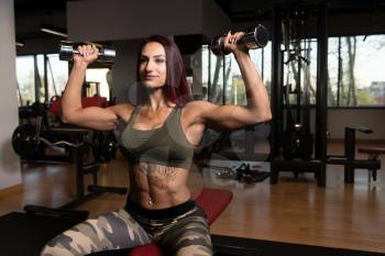 Woman Exercising Shoulders With Dumbbells In The Gym And Flexing Muscles - Muscular Athletic Bodybuilder Fitness Model Doing Dumbbell Concentration Curls
