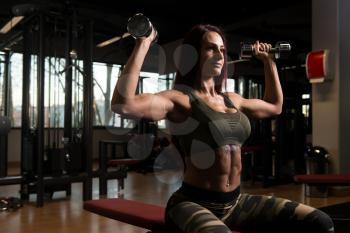 Woman Exercising Shoulders With Dumbbells In The Gym And Flexing Muscles - Muscular Athletic Bodybuilder Fitness Model Doing Dumbbell Concentration Curls