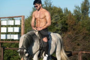 Handsome Macho Man Cowboy Riding on a Horse - Background of Sky and Mountains