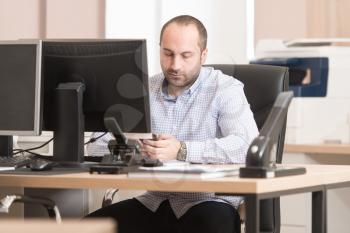Young Handsome Businessman Working With Computer At Desk In The Modern Office Talking On Phone