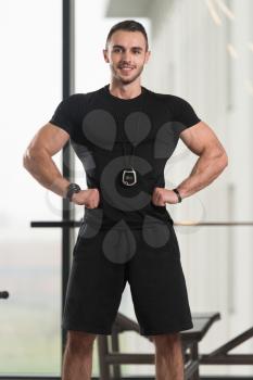 Handsome Personal Trainer With Stopwatch In A Fitness Center Gym Standing Strong