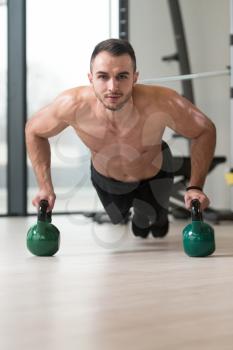 Healthy Man Athlete Doing Pushups Workout With Kettle Bell In A Gym - Kettle-bell Exercise