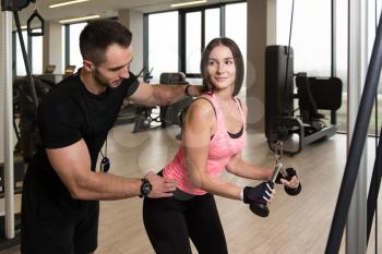 Personal Trainer Showing Young Woman How To Train Triceps In The Gym