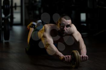 Young Man Wearing Glasses Exercising Fitness Workout For Abdominal With Toning Wheel