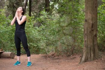 Young Woman Stretching Before Running In Wooded Forest Area - Training And Exercising For Trail Run Marathon Endurance - Fitness Healthy Lifestyle Concept