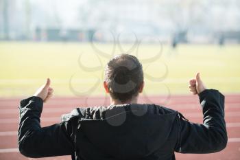 Back View of Young Man Sitting on Seat or Bleachers Sports Tribune and Cheering for His Favourite Team